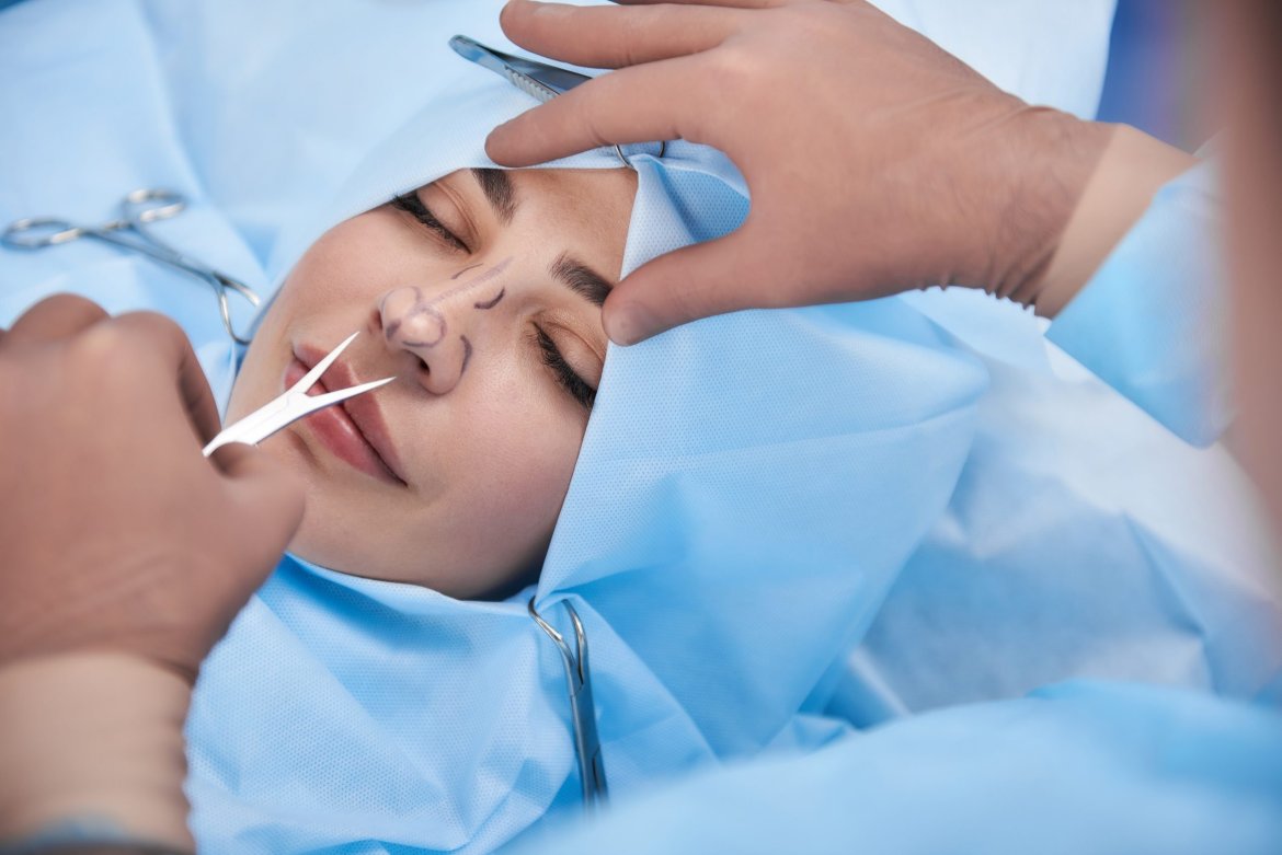 Surgeon making rhinoplasty for young beautiful woman AdobeStock 236305491 scaled